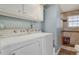 Functional laundry area with washer, dryer, upper cabinets, and adjacent tiled shower at 9590 W Eureka Pl, Lakewood, CO 80227