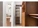 Walk-in closet showing custom wood shelving and drawers for optimal organization next to the bathroom vanity at 14023 W Amherst Pl, Lakewood, CO 80228