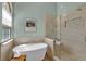 Bathroom with soaking tub, gray tiled walk-in shower, hardwood floors, and white walls at 7340 Brixham Cir, Castle Pines, CO 80108