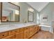 Bathroom featuring double sinks, wood cabinets, hardwood flooring, and a soaking tub for relaxation at 7340 Brixham Cir, Castle Pines, CO 80108
