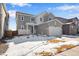 Charming two-story home with a front-facing garage, snowy yard, and inviting covered porch at 10022 Wheeling St, Commerce City, CO 80022