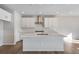 Modern kitchen with an island, white cabinets, and a stainless steel range hood at 10022 Wheeling St, Commerce City, CO 80022