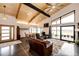 Spacious open-concept living room with exposed wooden beams, leather furniture, and large windows at 43010 Ptarmigan Ranch St, Parker, CO 80138