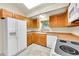 A well-lit kitchen with wood cabinets, white appliances, and a window overlooking the yard at 18022 E Loyola Pl, Aurora, CO 80013