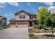 Two-story home featuring a three-car garage, stone accents, and landscaped front yard on a sunny day at 19347 E 65Th Ave, Aurora, CO 80019
