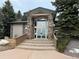 Clubhouse entrance featuring stone pillars, glass doors, and a gable roof, surrounded by mature pine trees at 8430 Little Rock Way # 102, Highlands Ranch, CO 80126