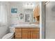 Cozy bathroom features wood cabinets, a decorative mirror, and tiled shower at 11880 W 30Th Pl, Lakewood, CO 80215