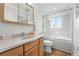 Bright bathroom featuring tiled floors, wood vanity, and shower/tub combo at 11880 W 30Th Pl, Lakewood, CO 80215