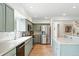 Modern kitchen with stainless steel appliances, light green cabinetry, and hardwood floors at 11880 W 30Th Pl, Lakewood, CO 80215