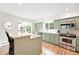 Well-lit kitchen featuring stainless steel appliances, light green cabinets, and views of the backyard at 11880 W 30Th Pl, Lakewood, CO 80215