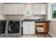 Well-lit laundry room with modern washer and dryer, custom cabinets, and decorative window at 11880 W 30Th Pl, Lakewood, CO 80215
