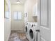 Bright laundry room with side-by-side washer and dryer, white cabinets, and tile flooring at 8559 W 93Rd W Ct, Broomfield, CO 80021