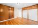 Bedroom with hardwood floors, wooden accent wall, and built-in storage cabinets at 10505 Lowry Pl, Aurora, CO 80010
