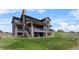 Back exterior of a home with stone accents, wood siding, multiple decks, and a well-manicured lawn at 1587 Arrowpoint Ct, Franktown, CO 80116