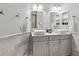 Well-lit bathroom featuring double sinks, vanity, decorative mirrors, and a glass-enclosed shower at 9895 Wyecliff Dr, Highlands Ranch, CO 80126