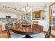 Dining room with a round table, chandelier, hardwood floors, and flows into kitchen and living room at 9895 Wyecliff Dr, Highlands Ranch, CO 80126