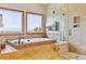 Luxurious bathroom with a soaking tub, glass shower, and scenic views from two large windows at 9895 Wyecliff Dr, Highlands Ranch, CO 80126
