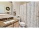 Traditional bathroom with granite counters, single sink, decorative mirror, and floral shower curtain at 9486 Elmhurst Ln # D, Highlands Ranch, CO 80129