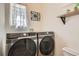 Convenient laundry room with side-by-side washer and dryer, a window, and a shelf at 9486 Elmhurst Ln # D, Highlands Ranch, CO 80129