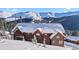 Stunning log home nestled in a snowy landscape with breathtaking mountain views in the background at 351 Kimmes Ln, Breckenridge, CO 80424