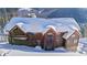 Exterior view of a snow-covered log home with icicles hanging from the roof, in a wooded landscape at 351 Kimmes Ln, Breckenridge, CO 80424