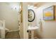 Charming powder room with a pedestal sink, decorative mirror and artwork, adjacent to stairs at 7777 E 23Rd Ave # 401, Denver, CO 80238