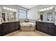 A centered bathtub is surrounded by dark wood vanities, tile backsplash, and modern lighting at 27423 E Euclid Dr, Aurora, CO 80016