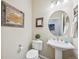 Cozy powder room with rustic-framed artwork, pedestal sink and round mirror at 27423 E Euclid Dr, Aurora, CO 80016