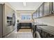 Bright laundry room with stainless steel refrigerator, dark cabinets, and washer/dryer at 27423 E Euclid Dr, Aurora, CO 80016