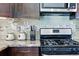 Close-up of stainless steel range with microwave and decorative tiled backsplash at 6231 Indian Paintbrush St # 214, Frederick, CO 80530
