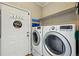 Bright laundry room with washer, dryer, and white door with coat hooks at 6231 Indian Paintbrush St # 214, Frederick, CO 80530