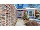 Home's inviting entrance features a decorative glass front door, brick accents, and manicured evergreen shrubs at 7464 Shoreham Pl, Castle Pines, CO 80108