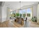 Bright dining room with modern light fixture, wood table, bench, large windows and sliding glass door to outdoor patio at 5078 S Quail St, Littleton, CO 80127
