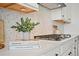 Close-up of modern kitchen with white cabinets, stylish backsplash, and cooktop at 5078 S Quail St, Littleton, CO 80127
