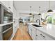Modern kitchen with white cabinets, a stainless oven, and island with view into living room at 5078 S Quail St, Littleton, CO 80127