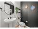 Stylish powder room featuring a pedestal sink, dark walls, and decorative mirrors at 5078 S Quail St, Littleton, CO 80127