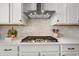 A close up on a stovetop with mosaic backsplash and white cabinets at 5078 S Quail St, Littleton, CO 80127