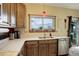 Charming kitchen features light countertops, wood cabinetry, stainless steel dishwasher, and window with views at 11701 Elkhart St, Commerce City, CO 80603