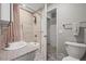 Bathroom with a shower over the tub, tiled walls, granite vanity and view of the door to the hallway at 4942 Grove St, Denver, CO 80221