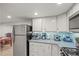 This kitchen boasts stainless steel appliances, ample counter space, and sleek white cabinetry at 4942 Grove St, Denver, CO 80221