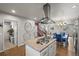 Open-concept kitchen features an island gas cooktop, modern hood, and view into dining and living spaces at 4942 Grove St, Denver, CO 80221