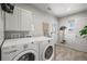 Laundry room with front load washer and dryer, white cabinets, and tile floors at 4942 Grove St, Denver, CO 80221