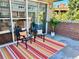 Relaxing patio with two chairs, throw pillows, rug, sliding glass door access, and brick wall at 1441 Central # 305, Denver, CO 80211