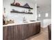 Elegant wet bar with dark wood cabinetry, white countertops, and stylish shelving at 43 S Oneida Ct, Denver, CO 80230