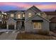 Two-story house with gray siding, stone accents, and solar panels at dusk at 10993 Ledges Rd, Parker, CO 80134