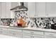 Well-equipped kitchen showcasing white cabinets, stainless steel range hood, and designer backsplash at 10993 Ledges Rd, Parker, CO 80134
