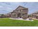 Beautiful two-story home with a well-maintained lawn, stone accents, and an outdoor patio with seating at 12578 Hudson Ct, Thornton, CO 80241