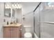 Bright bathroom with a mirrored vanity, toilet, and glass-enclosed shower at 20835 E 47Th Ave, Denver, CO 80249