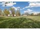 Large, open backyard with trees, sheds, chicken coop, and playground equipment on a sunny day at 1866 Mountain View St, Erie, CO 80516
