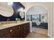 Bathroom with double sink vanity and gold fixtures, adjoins a carpeted bedroom at 1866 Mountain View St, Erie, CO 80516